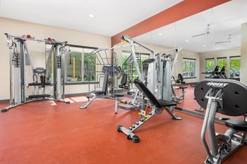 A gym with a red floor and various exercise machines.